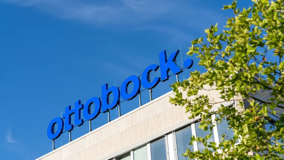 Ottobock building with large logo under clear blue sky and surrounding trees
