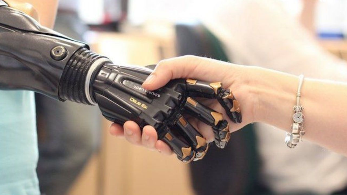 Human hand shaking a robotic prosthetic hand in a tech setting